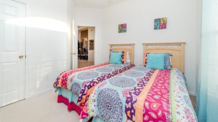 Bedroom 4 with two twin beds with bight patterned sheets.