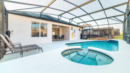 Outdoor pool area with spa and loungers.